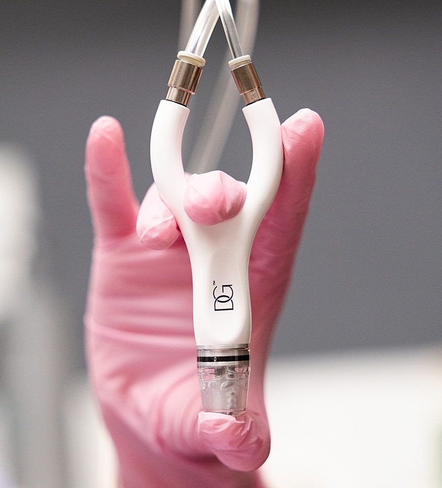 Hand holding a medical device with pink gloves.