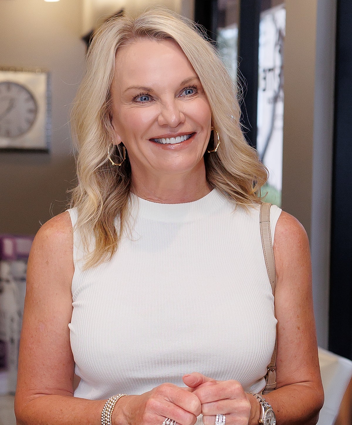 Smiling woman with blonde hair in light outfit.