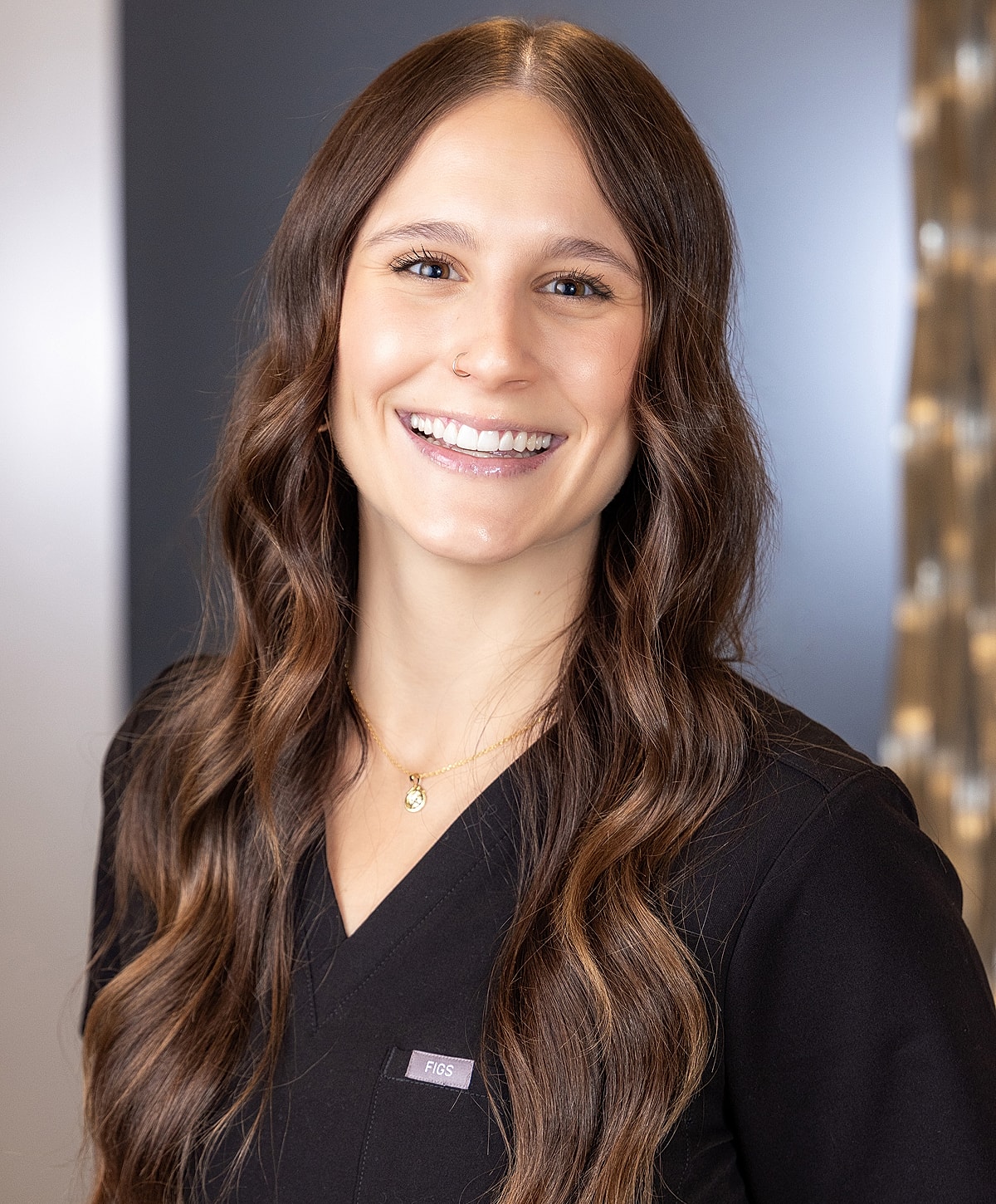 Smiling woman in scrubs with long hair.